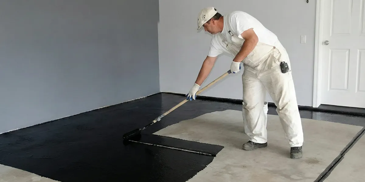 basement waterproofing professional applying waterproof coating to protect a basement floor in Oklahoma City, OK